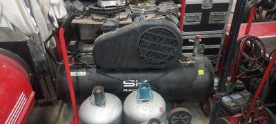 two air compressors sitting next to each other in a room