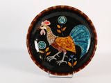 une photo d'une assiette décorative sur laquelle figure un coq