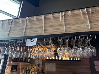 many wine glasses hanging from the ceiling of a bar