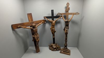 trois crucifix en bois posés sur une étagère dans une pièce