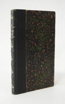 un vieux livre à la couverture noire posé sur une surface blanche