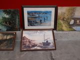 many paintings on the ground next to a red wall