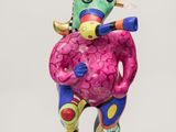 sculpture of a colorful figure holding a pink object on a black base