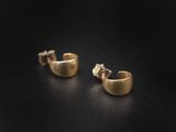 a pair of gold earrings on a black surface