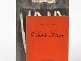 un vieux livre à la couverture rouge posé à côté d'une photo en noir et blanc