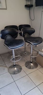 quatre tabourets de bar en cuir noir dans un coin de la pièce
