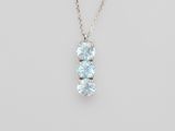 un collier en or blanc orné de trois topazes bleues montées sur une chaîne