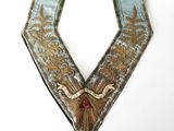 un gros plan d'un collier bleu et or sur fond blanc