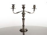 un candélabre en argent avec trois bougies posé sur une table