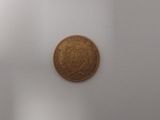 une pièce de monnaie marron posée sur une surface blanche dans une pièce