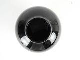 a black vase sitting on a white table with a white background