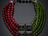 a close up of a necklace on a black background with red and green beads