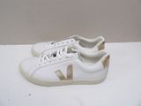 the white and gold sneakers are sitting on a white surface