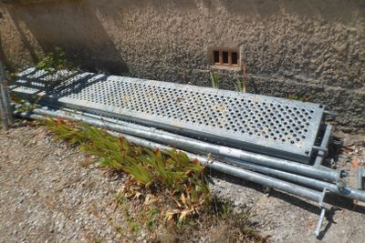 a metal bench sitting on the side of a building