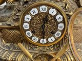 a gold clock with a bird on top of it