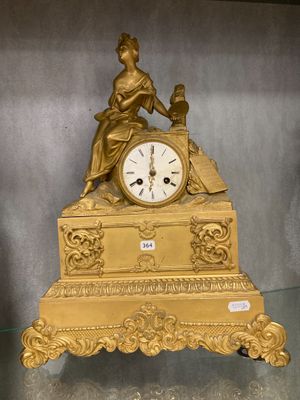 a gold clock sitting on a glass shelf in a room