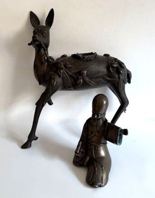 statue en bronze représentant un homme agenouillé à côté d'une statue de cerf