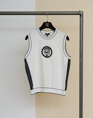 un pull blanc orné d'une fleur noire et blanche, suspendu à un portant