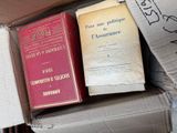 two books sitting in a cardboard box on the floor