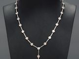 a silver necklace with a cross and pearls on a mannequin