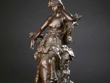 a bronze statue of a woman sitting on top of a rock