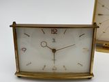 two clocks sitting next to each other on a white surface