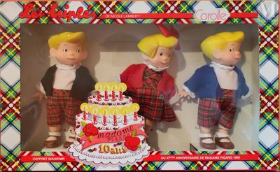 trois poupées dans une boîte sur laquelle est posé un gâteau