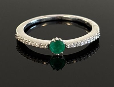 an image of a diamond and emerald ring on a black surface