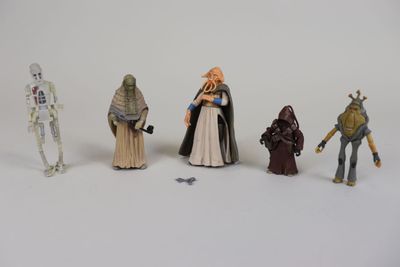 Plusieurs figurines de Star Wars sont alignées sur une surface blanche