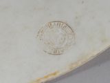 underside view of a white porcelain vase with a crest on it