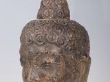 statue of a head of a buddha on a stand on a white surface