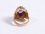 an image of a gold ring with a purple stone in it