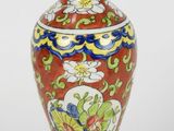 un vase rouge avec un socle doré sur fond blanc