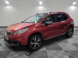 une voiture rouge est garée dans une pièce au sol en damier