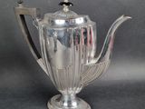 a silver tea pot with a handle on a table