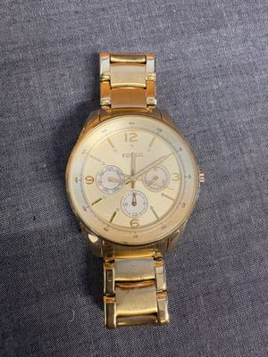 une montre en or avec un cadran blanc sur un fond gris
