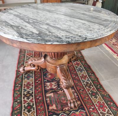 une table au plateau en marbre posée sur un tapis au sol