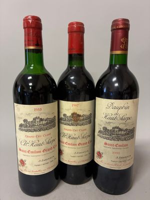 trois bouteilles de vin rouge sont alignées sur une surface blanche