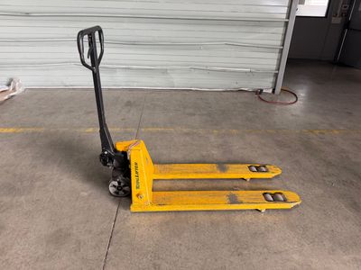 un chariot élévateur jaune posé au sol devant la porte d'un garage
