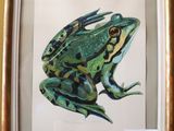 tableau représentant une grenouille verte dans un cadre doré, accroché à un mur jaune
