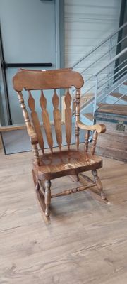 a wooden rocking chair sitting on a hard wood floor