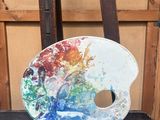 une palette de peinture posée sur une chaise devant un chevalet