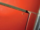 a close up of a red refrigerator door with a rusted handle