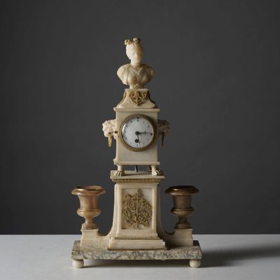 une horloge sur laquelle trône une statue, posée sur une table
