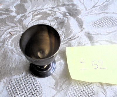 une petite tasse en métal posée sur une table, sur laquelle est posée une note