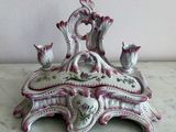 une table blanche et rose avec un vase et un bougeoir