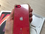 someone is holding a red iphone in their hand on a table