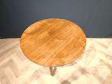 a round wooden table with a metal base on a wooden floor