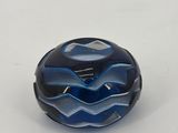 a close up of a blue and black glass bead on a white surface