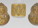 three brass plaques with a crown, shield, and shield on a white background